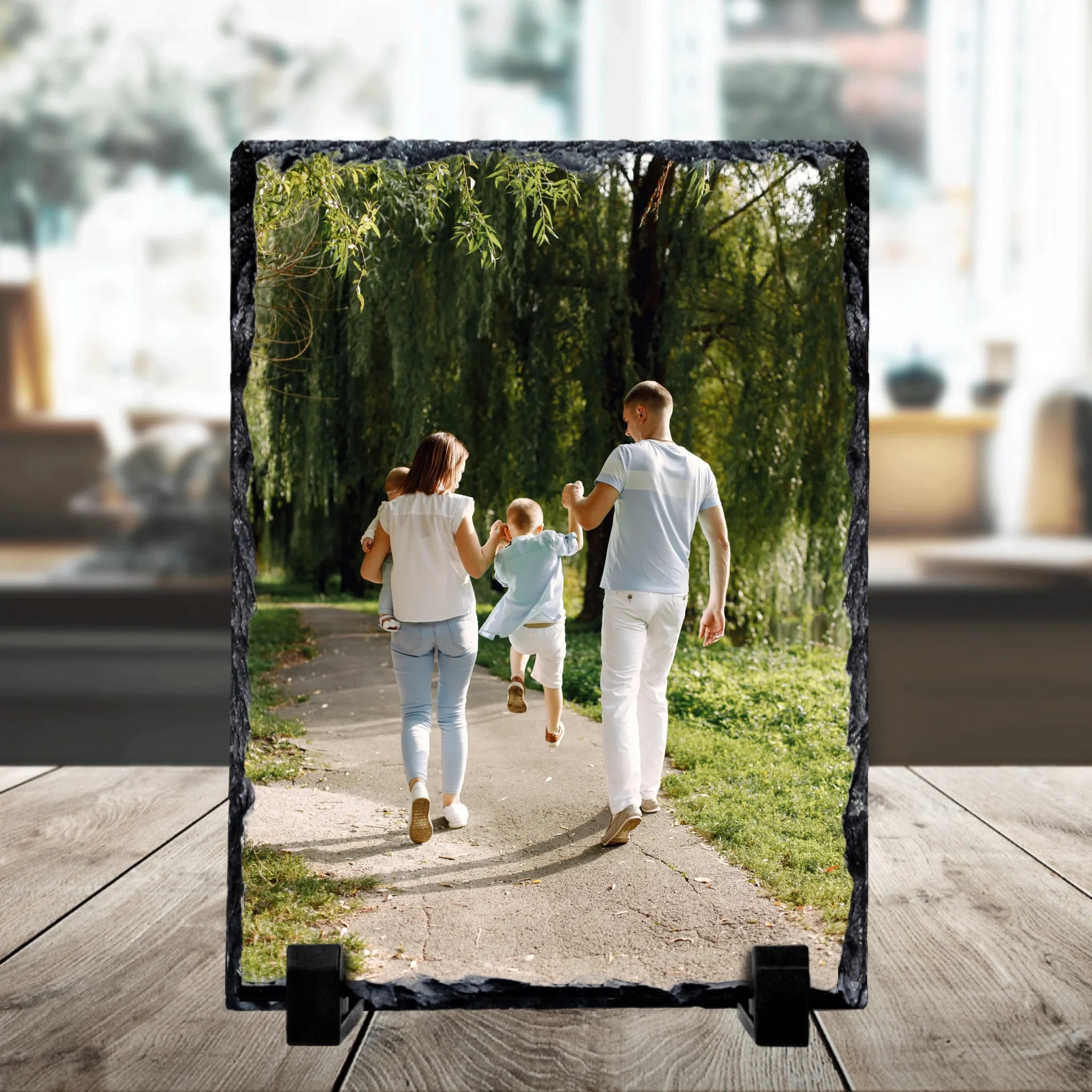 Personalised square photo slate on a stand printed with a family of four walking along a park path under willow trees.