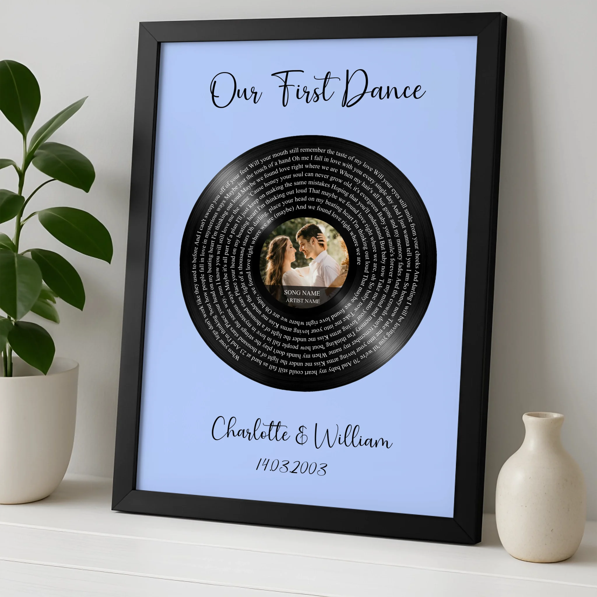 Black framed personalised vinyl record lyrics print on blue, couple's wedding photo at centre, names Charlotte and William, l