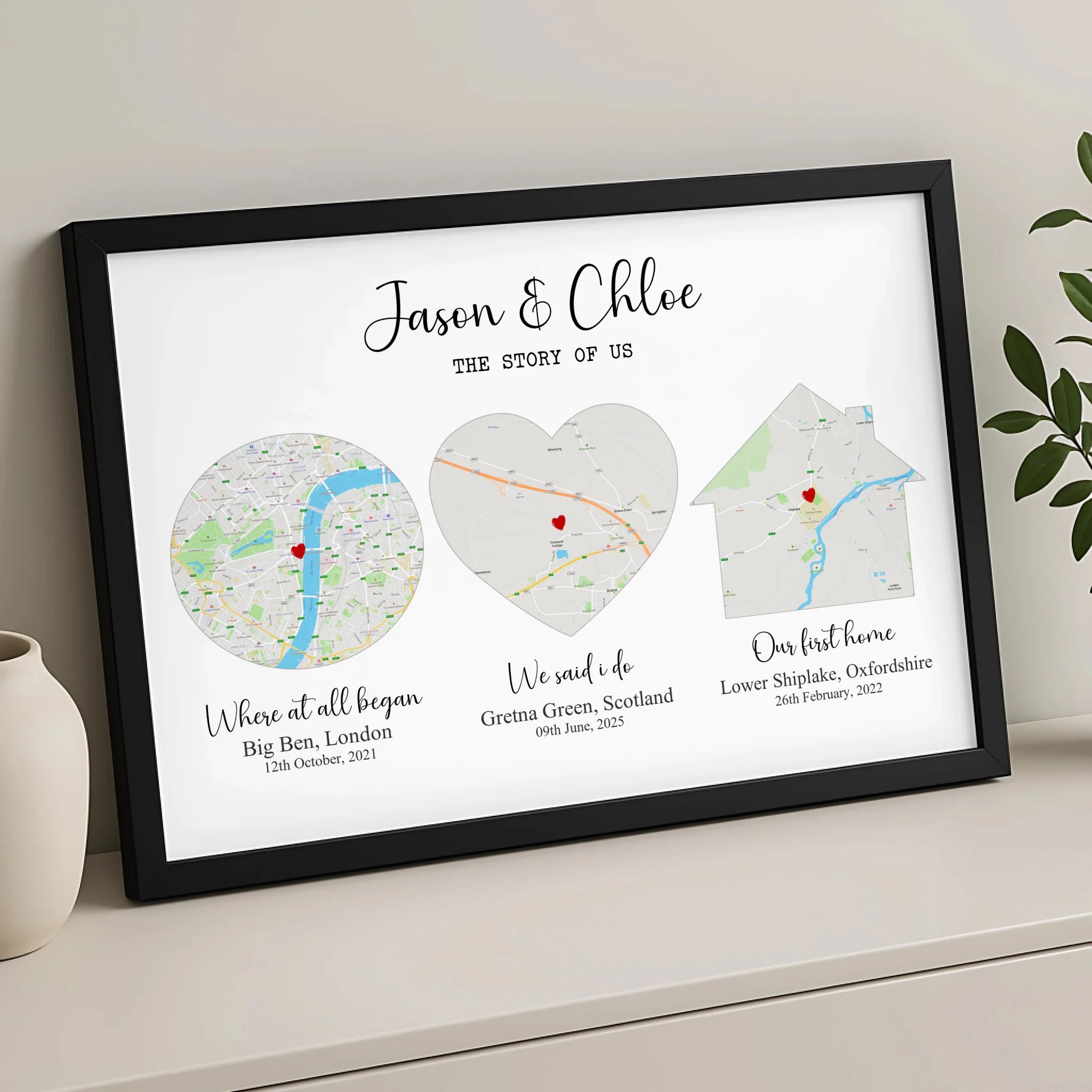 Black framed Story of Us couples map print, three location maps shaped as circle, heart and house, leaning against a grey wal
