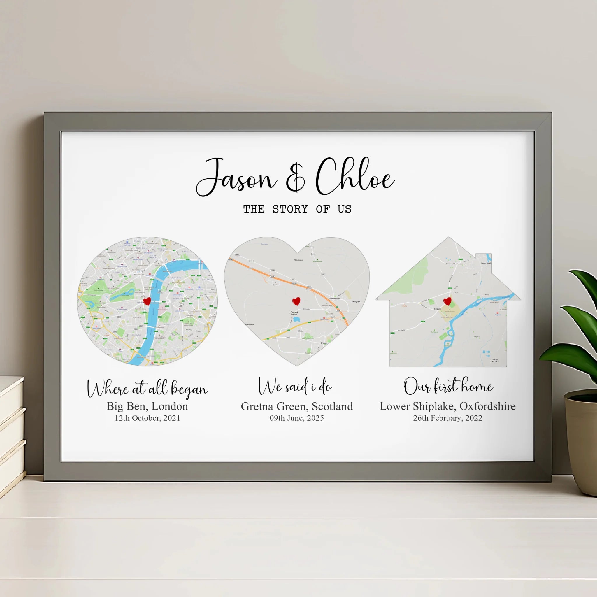 Grey framed Story of Us couples map print on a shelf with stacked books and a plant, three maps showing London, Scotland and