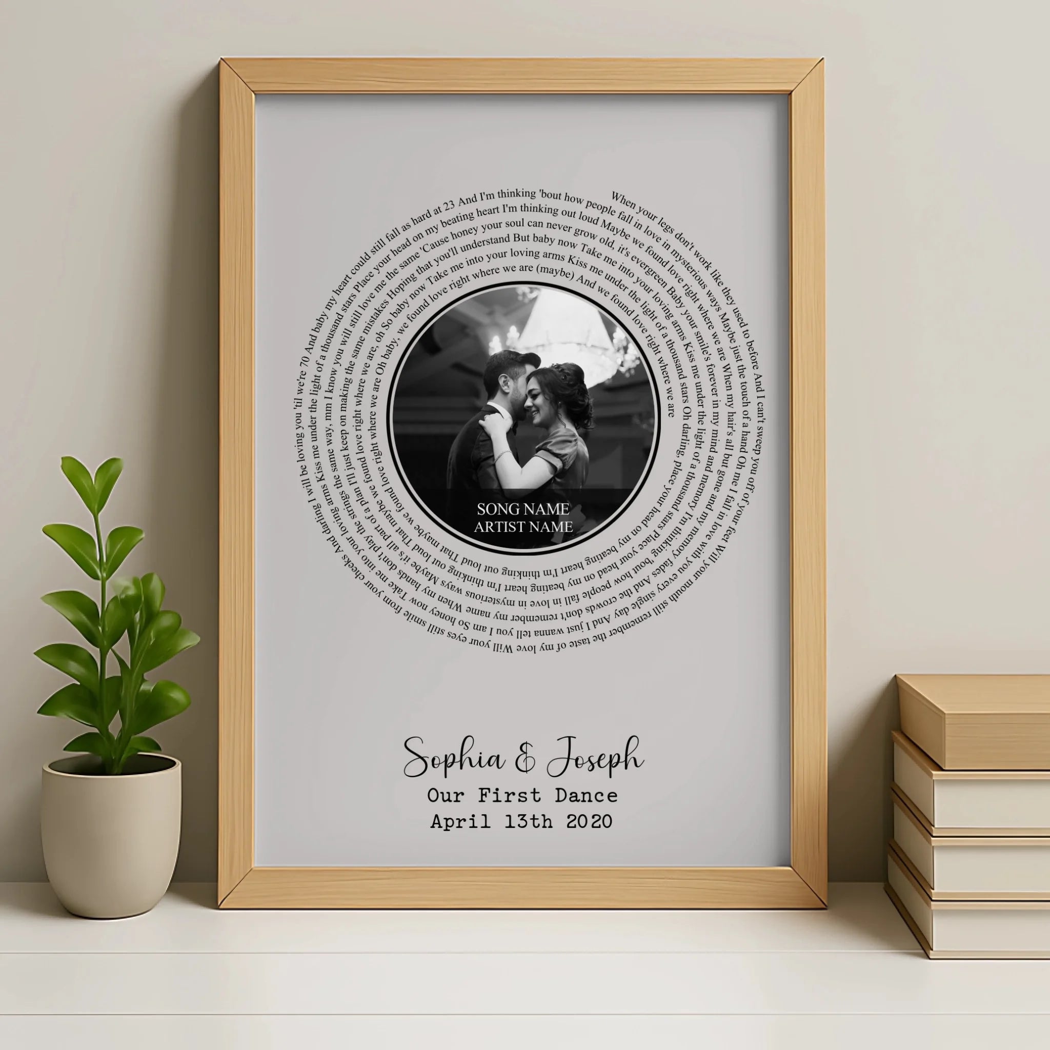 Natural wood framed spiral wedding song lyric print on shelf beside a plant and books, personalised for Sophia and Joseph, Ap