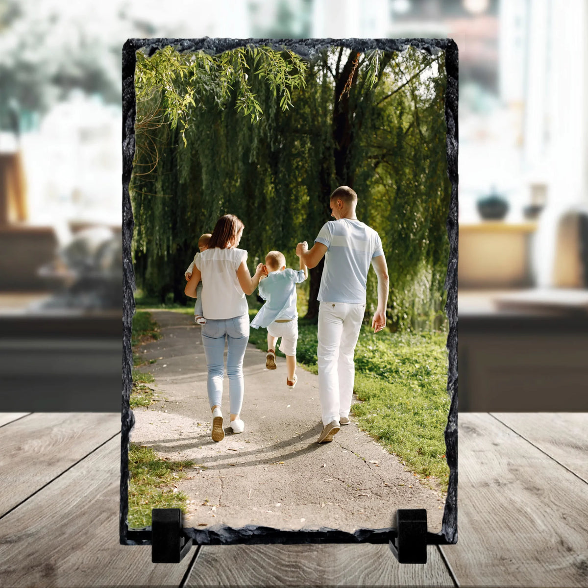 Personalised portrait photo slate on a stand printed with a family of four walking along a park path under willow trees.