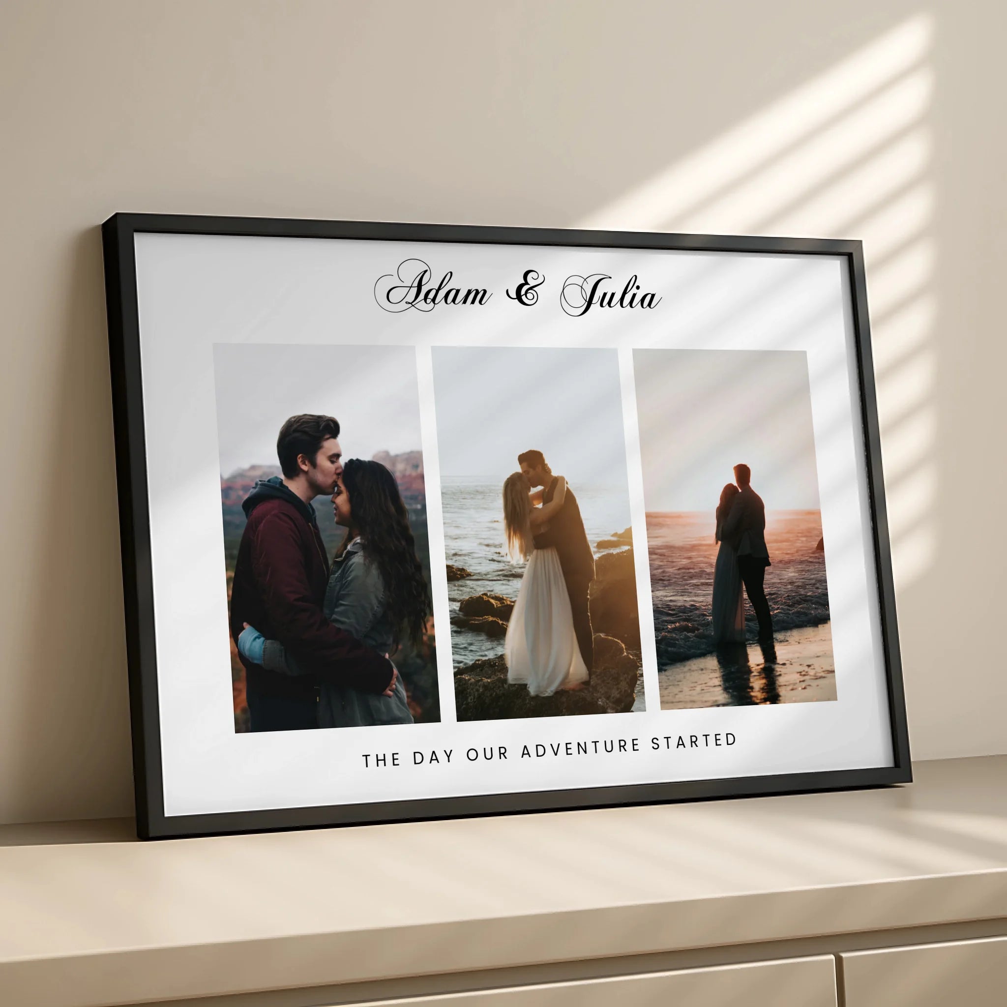 Black framed 3-photo personalised couple print with Adam and Julia script text, angled view showing side of frame in warm lig