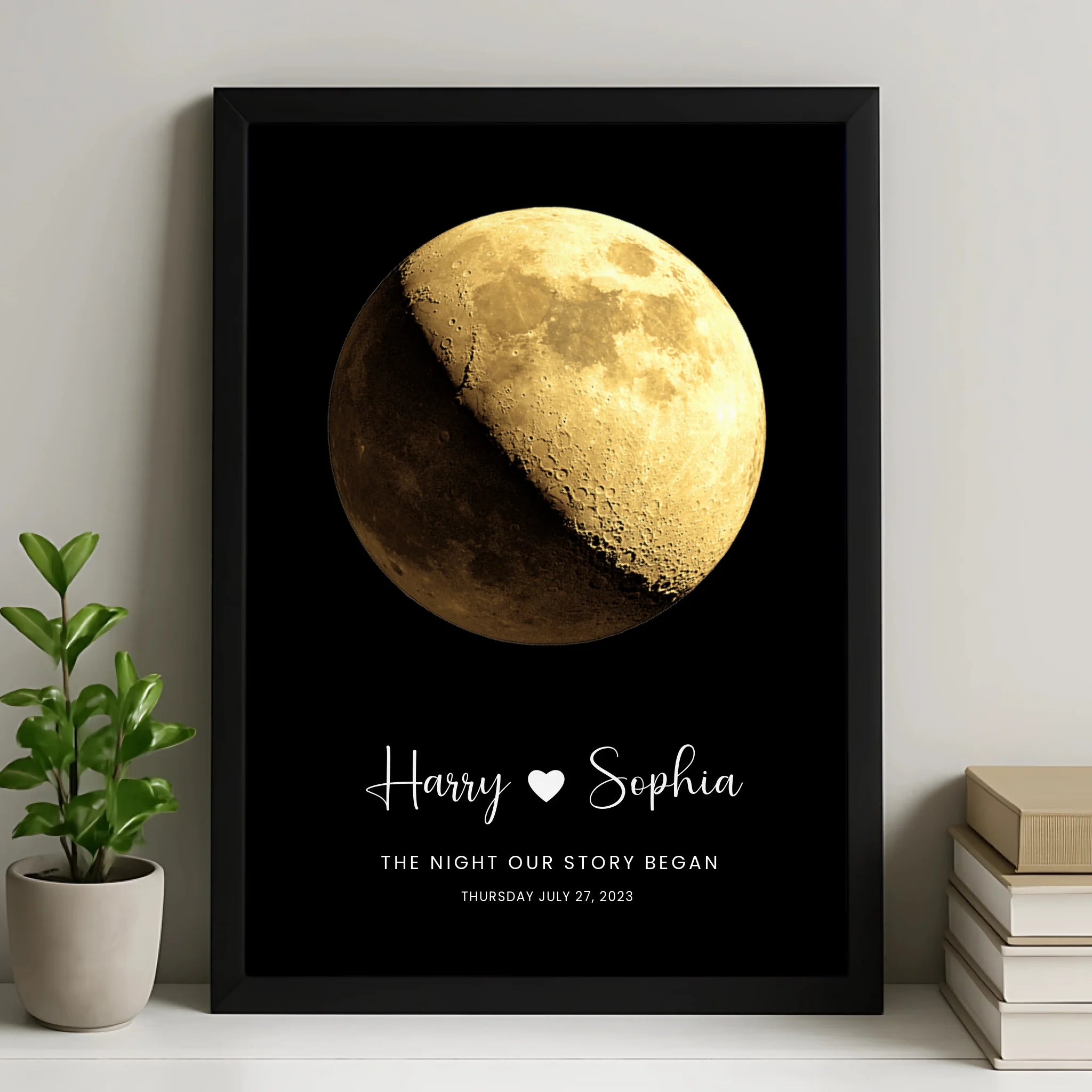 Black framed moon phase print personalised with Harry and Sophia, heart, and date Thursday July 27 2023, leaning on shelf wit