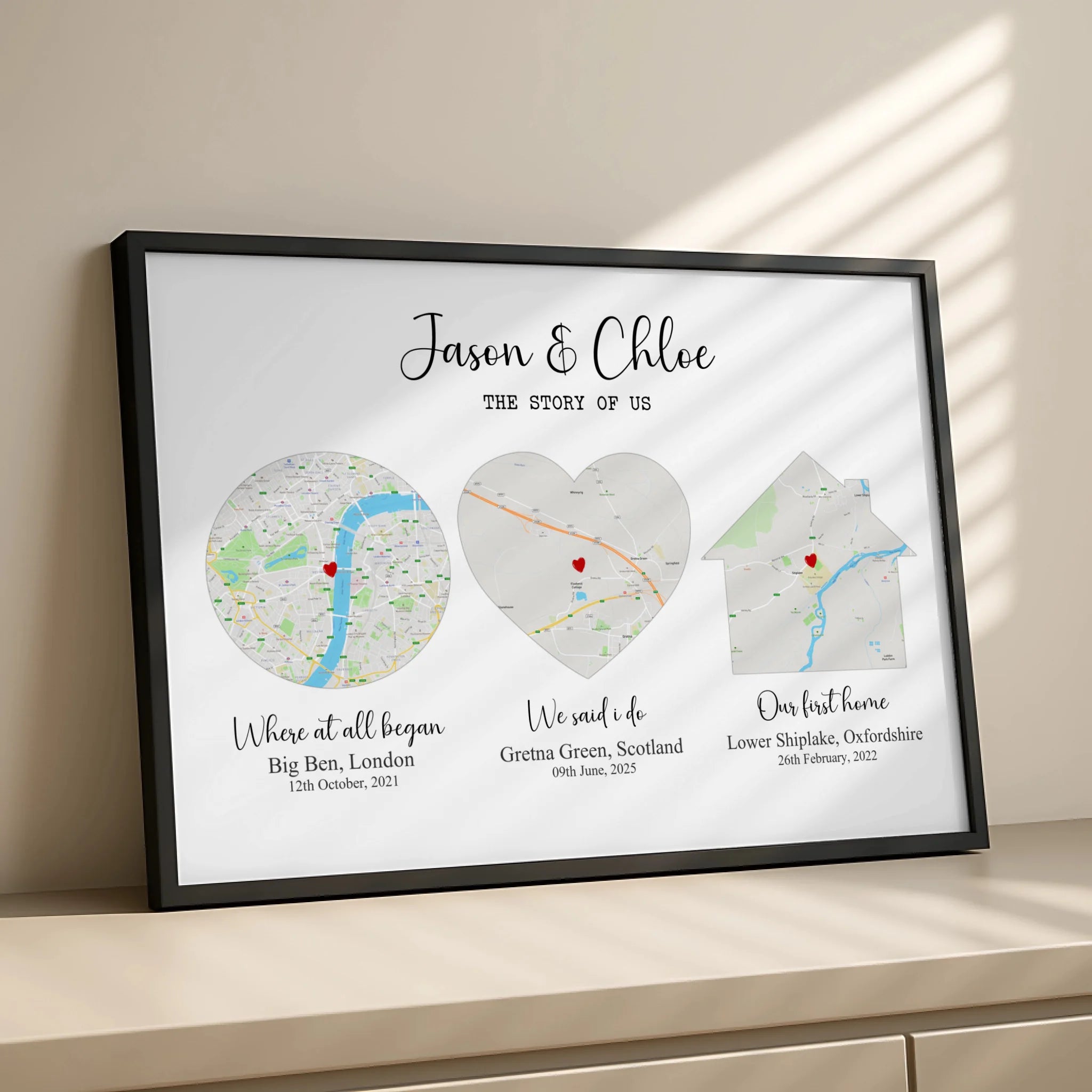Black framed Story of Us personalised map print on a sideboard in warm sunlight, showing London, Gretna Green and Oxfordshire